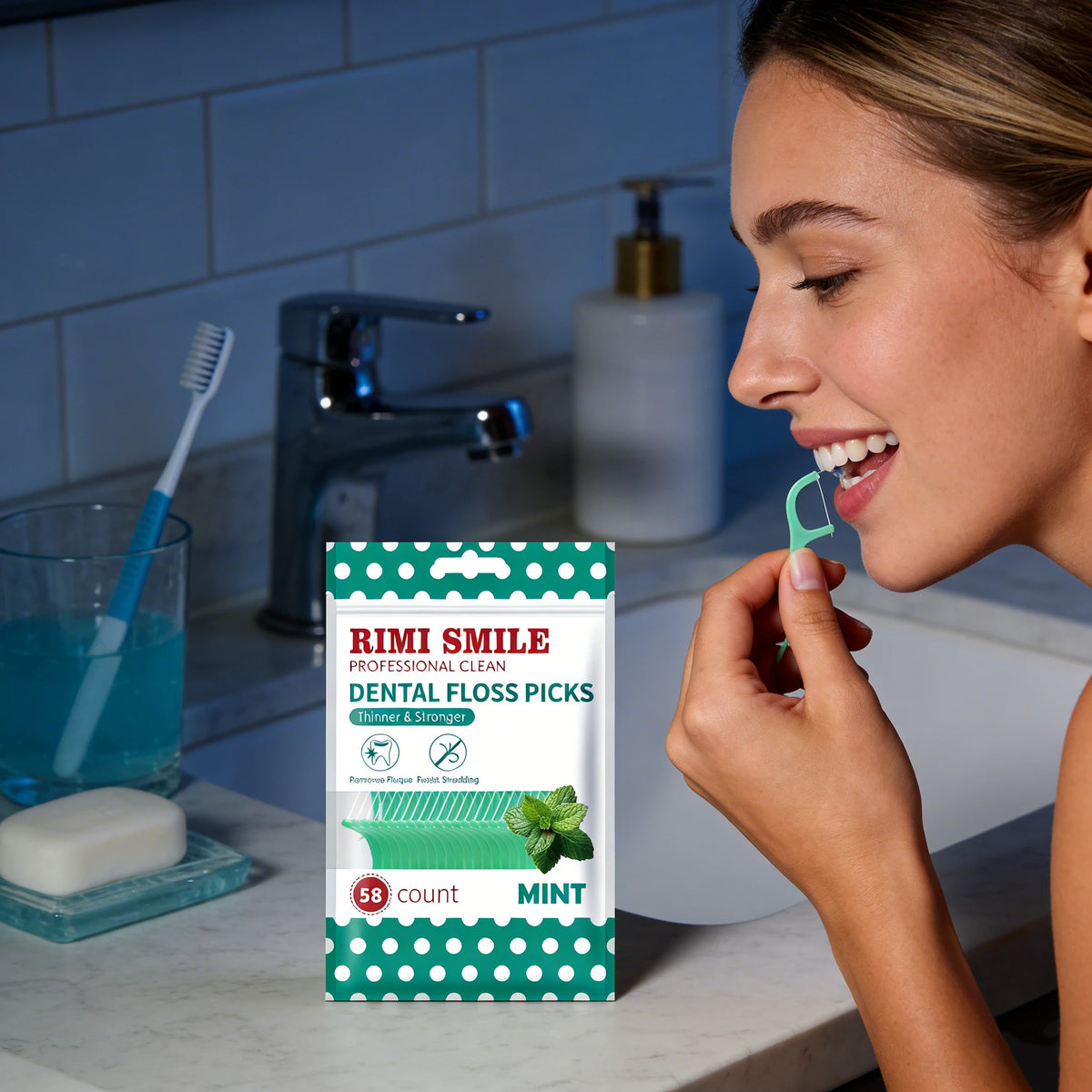 A woman uses mint flavored dental floss picks from a green and white case in a bathroom setting.