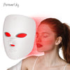 A woman applying a white facial mask with red LED lights to her face.