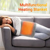A woman is relaxing on a couch with an orange heating blanket placed across her lap.