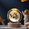 A glass crystal ball night light illuminates a detailed moon surface on a wooden base.