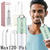 A man is holding a portable oral irrigator device with a green and silver body, demonstrating its use.