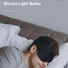 A man is sleeping comfortably with a black 3D eye mask on his face under white bedding.