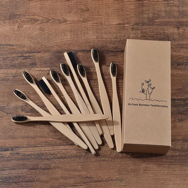 Une boîte en carton contenant dix brosses à dents en bambou posées sur une surface en bois.