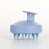 A light blue silicone body and scalp massage brush with a handle and multiple pointed bristles.