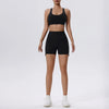 Una mujer modela un conjunto deportivo de yoga y gimnasio negro, compuesto por un top deportivo y shorts.