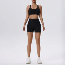 Eine Frau modelliert ein schwarzes Yoga- und Gym-Set mit Sports-BH und Shorts.