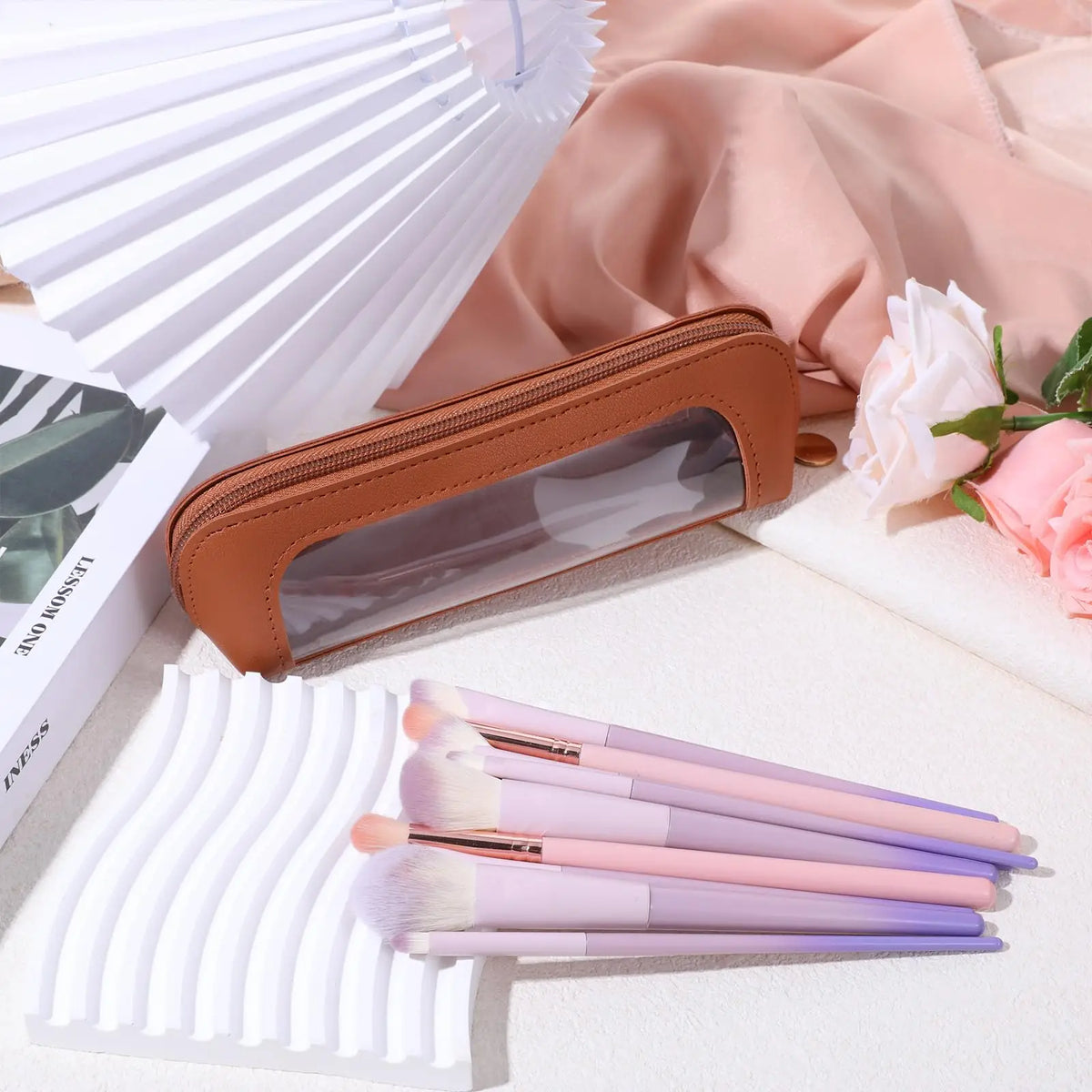 Braunes PU-Leder-Organizer-Beutel mit klarem Plastik und weißen Make-up-Pins auf einer hellen Oberfläche