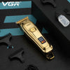 A gold-colored VGR cordless electric hair clipper with a battery indicator and attachments is shown on a dark surface.