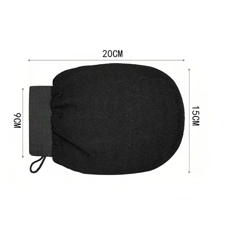 Gant pour gommage corporel noir avec sangle et élastique, montré à plat.