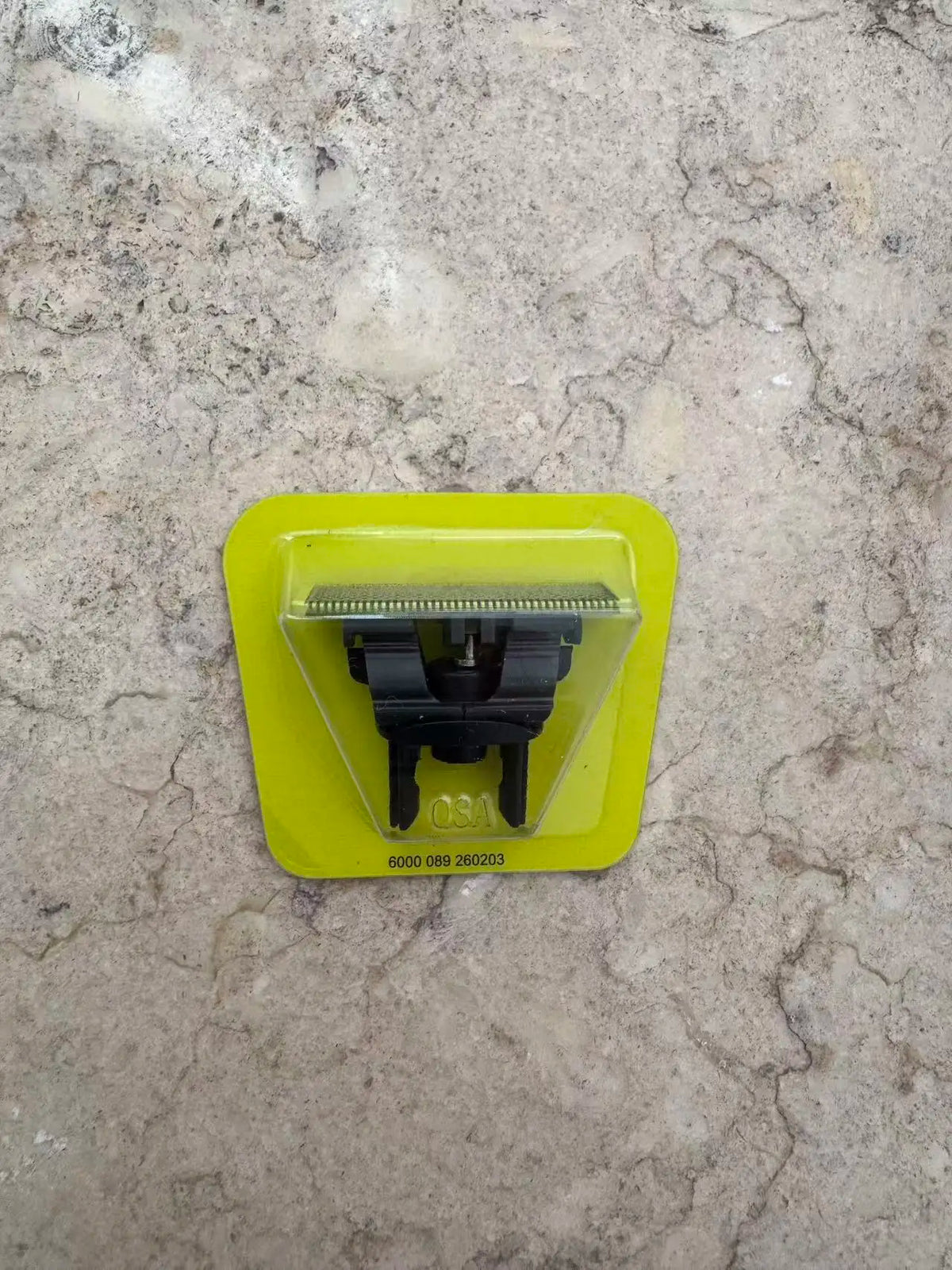 A yellow plastic precision electric beard trimmer with a black guard and branding visible on a light-colored stone surface.