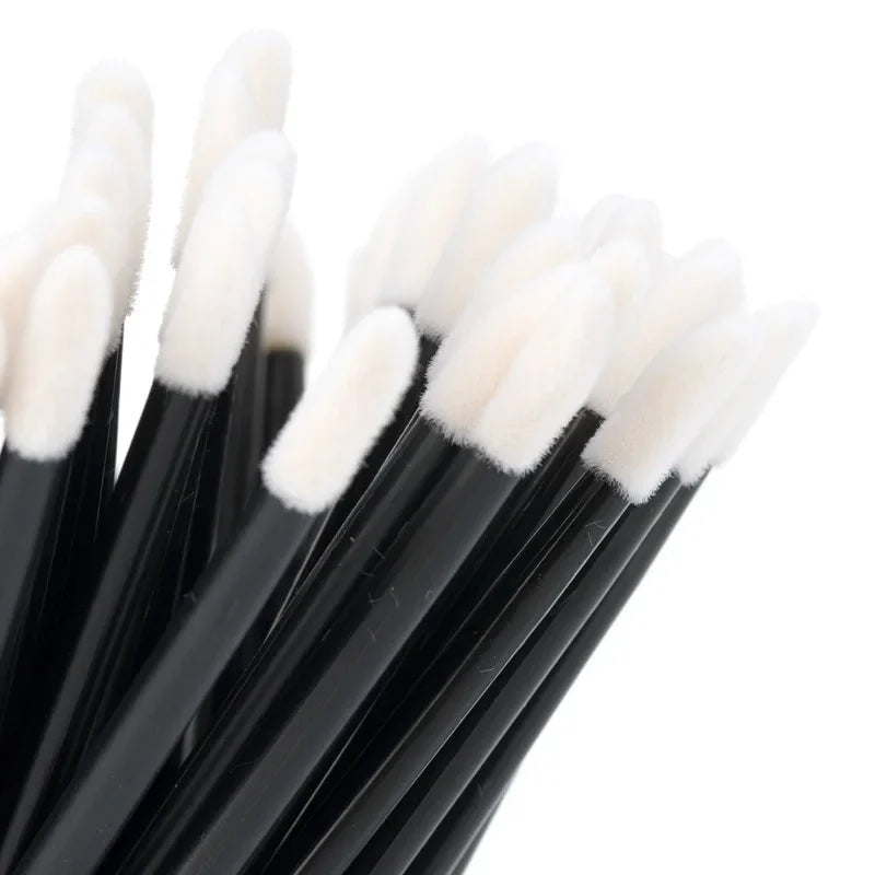 A set of black makeup brushes with white, fluffy bristles shown from above.