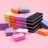 A collection of colorful, multi-sided nail and cuticle buffing files stacked in various shades of pink, orange, purple, yello