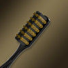A black toothbrush with yellow bristles is shown against a brown background.
