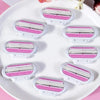 A set of three replacement shaving blades with pink and silver layers displayed on a white plate.