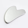 A silver stainless steel Gua Sha and ice roller facial massage set lying on a white surface.