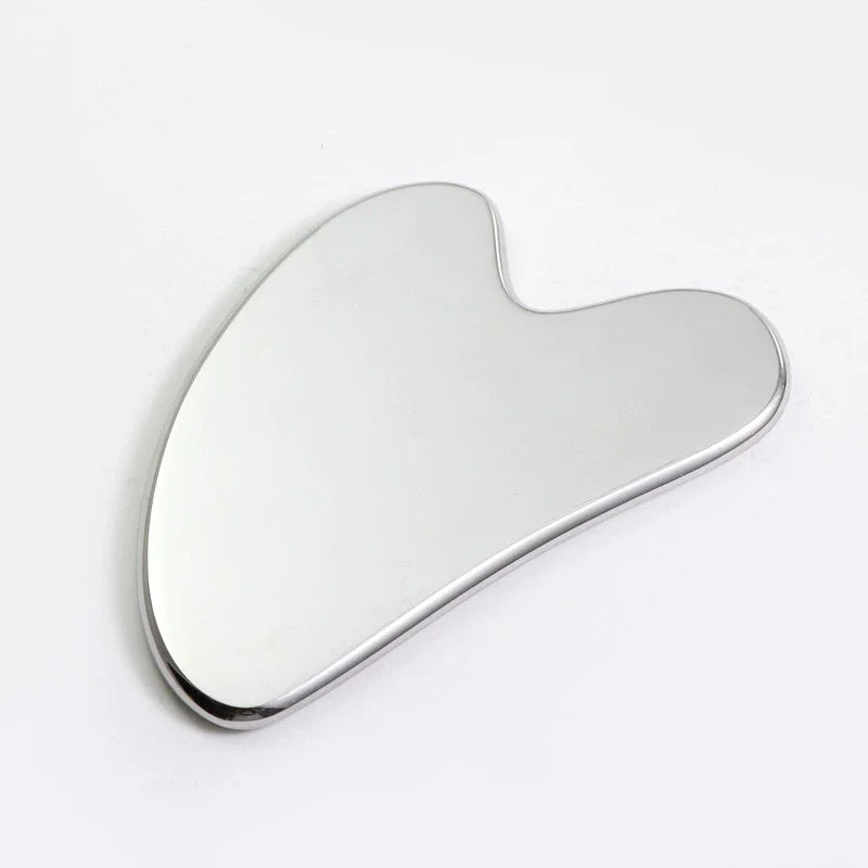 A silver stainless steel Gua Sha and ice roller facial massage set lying on a white surface.