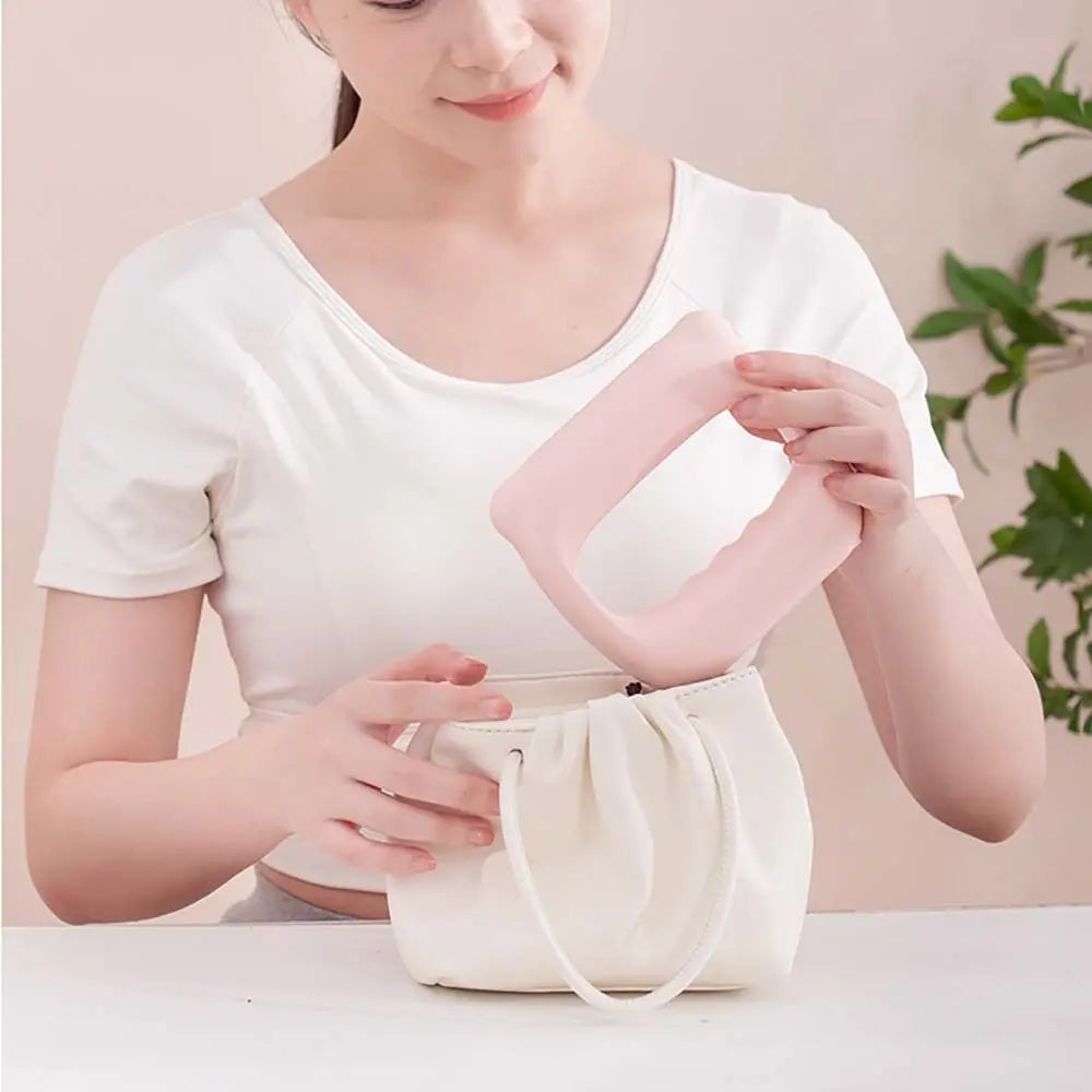 A woman holds a cream-colored portable electric fascia massager belt against her torso.