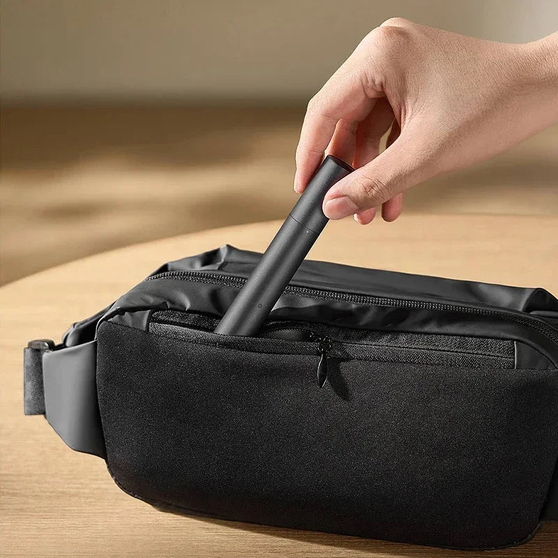 A hand is using a black electric nose and eyebrow hair trimmer inside a black zippered pouch.