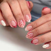 Close-up of hands displaying red and pink polka dot press-on nails on an almond shape.