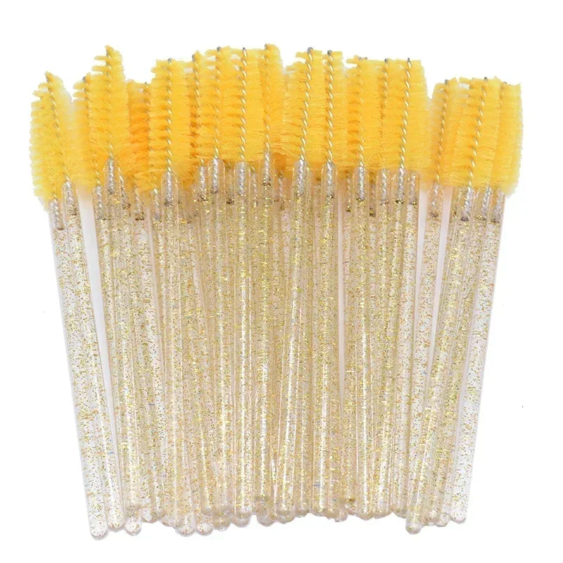 A set of disposable yellow eyelash and eyebrow brushes with clear handles.