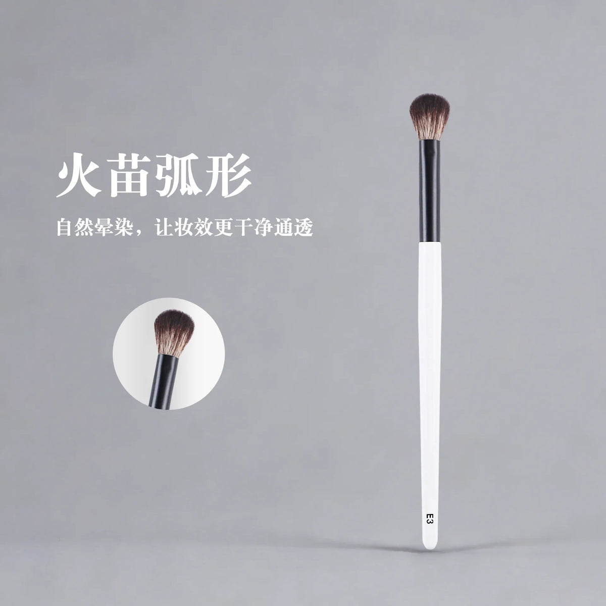A long, white makeup brush with a dark ferrule and a fluffy brown bristles is shown against a gray background.