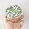 A hand holds an air cushion makeup puff set with a clear storage box and a green band.