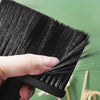A hand is holding a black soft bristle hair duster brush, showing the dense bristles and handle.