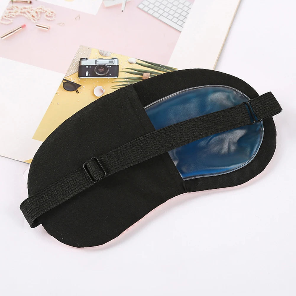 Masque pour les yeux noir apaisant avec un insert bleu sur fond rose pâle.
