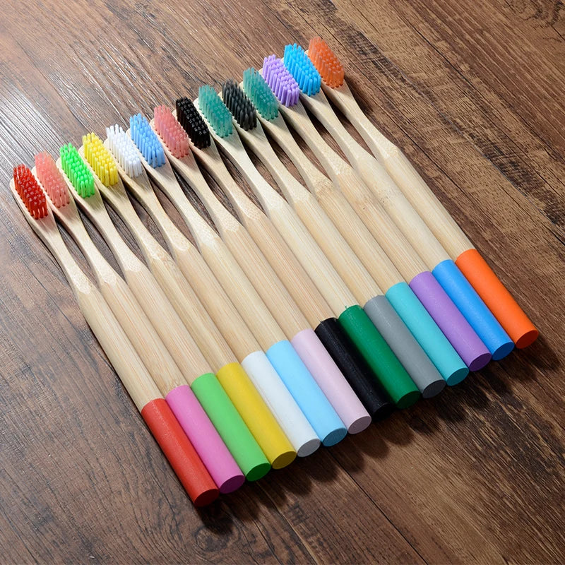 A pack of ten eco-friendly bamboo toothbrushes in various colors arranged diagonally on a wooden surface.