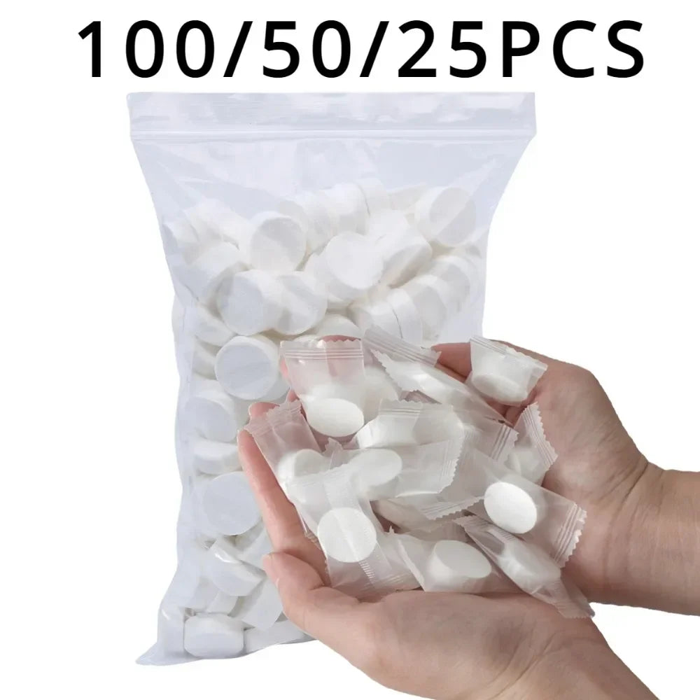 A hand holds a bag of 100/50/25 pieces of white reusable compressed face towels.