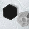 A black silicone facial cleaning and massage brush resting on clear water.