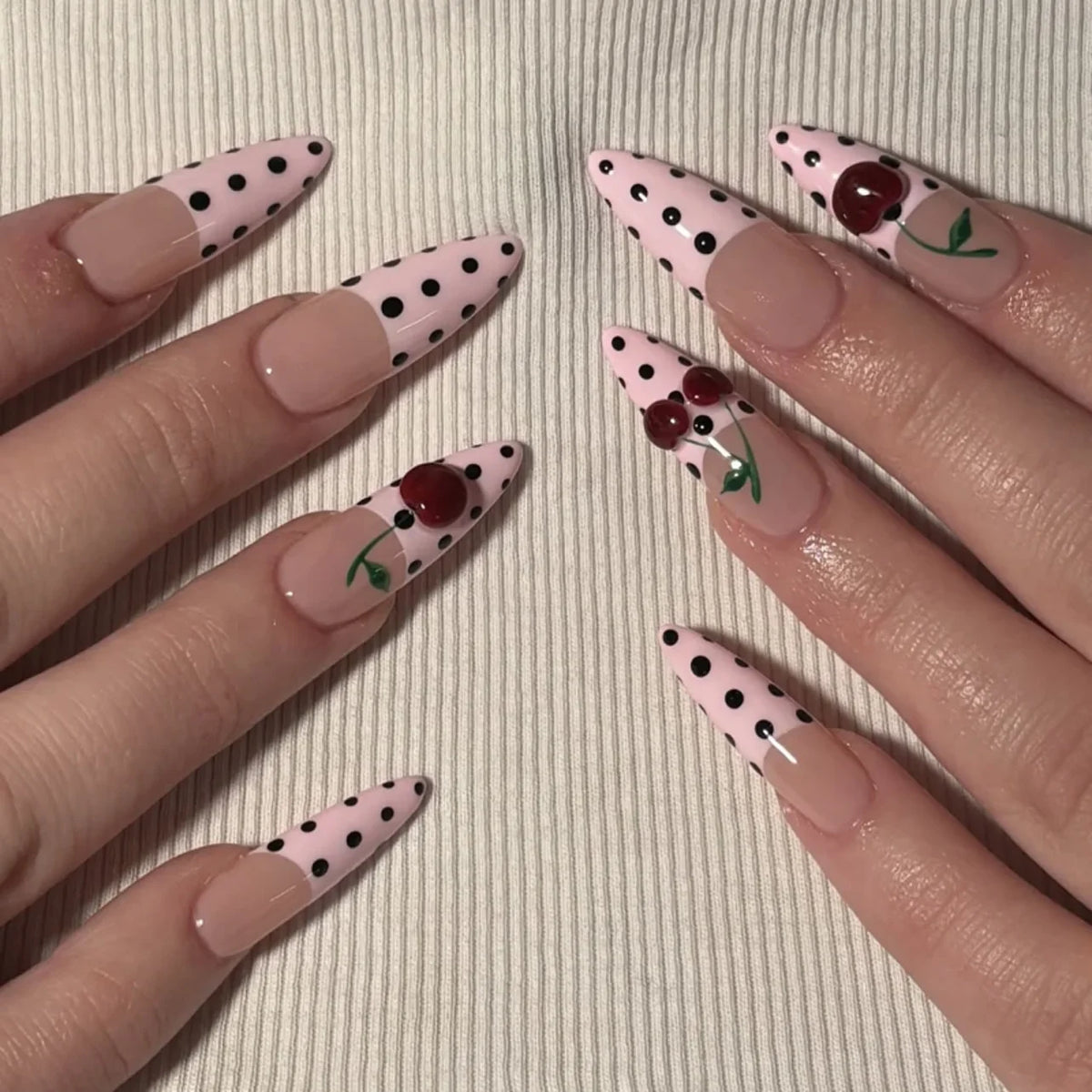 Gros plan sur plusieurs ongles pressés en forme d'amande avec des motifs floraux roses et verts.