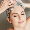 A woman is using a smart head massager to refresh her scalp and face with water.