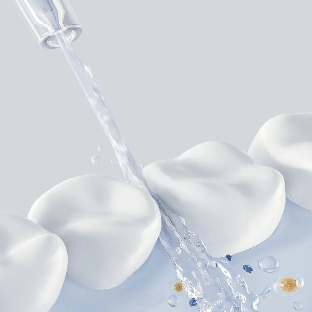 A close-up of a white portable cordless oral irrigator device spraying water onto a light blue surface.