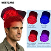 A man wearing a red light therapy cap, demonstrating the use of an infrared scalp massager device.