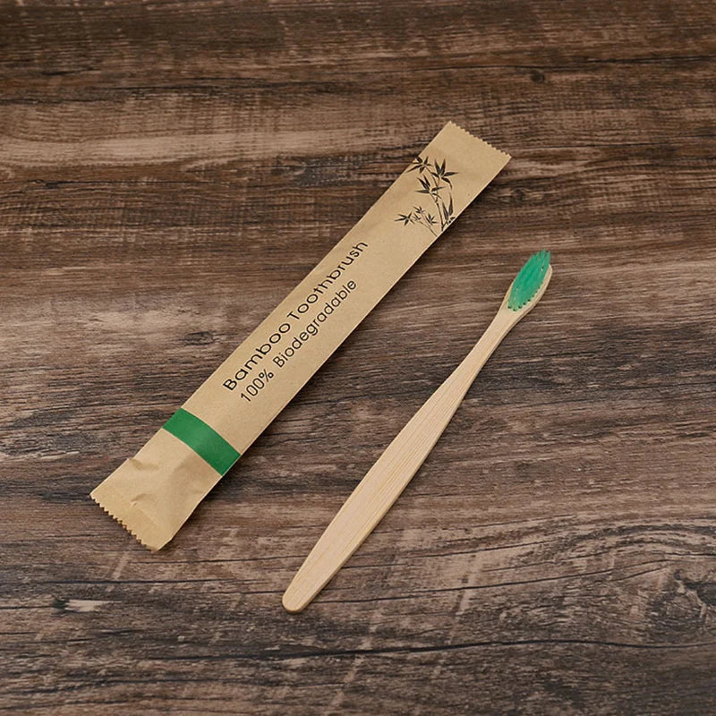 A bamboo toothbrush packaged on natural kraft paper, lying diagonally on a dark wooden surface.