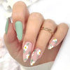 A hand displaying 24 press-on false nails with a pink base and white floral design and a gold bracelet.
