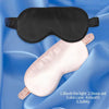 A pink silk eye mask with a black eye mask placed on a blue fabric background for sleep and relaxation.
