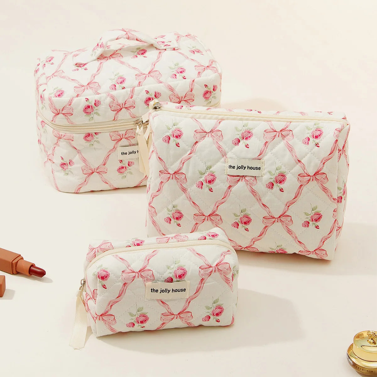 A collection of pink and white quilted cotton makeup bags with floral embroidery displayed on a light background.