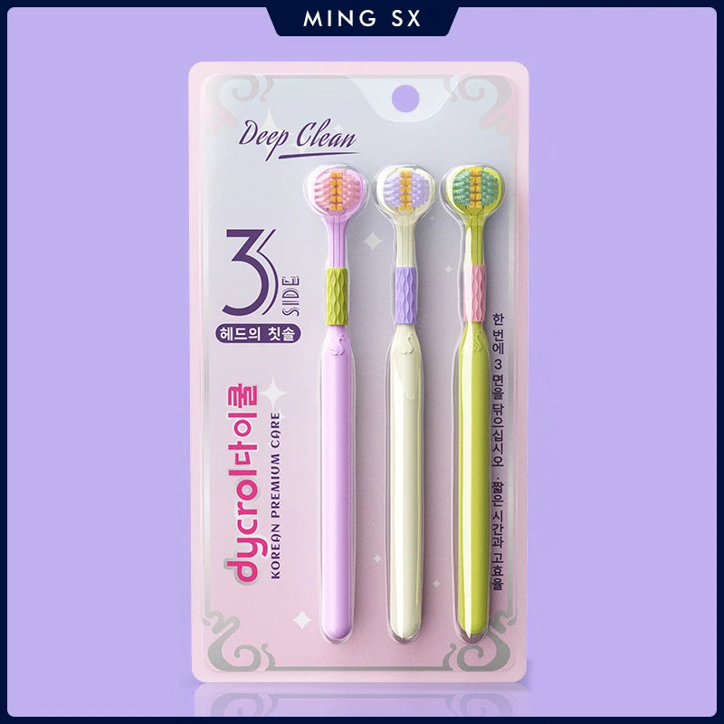 Une boîte rose contient un set de trois brosses à dents angulées avec des poils violets et verts.