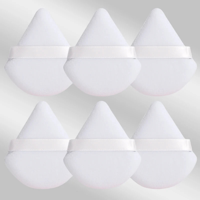 Un set de six éponges de maquillage triangulaires blanches avec des élastiques blancs.