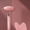 A pink heart-shaped facial massage roller with a metal handle and a separate heart-shaped scraping plate.