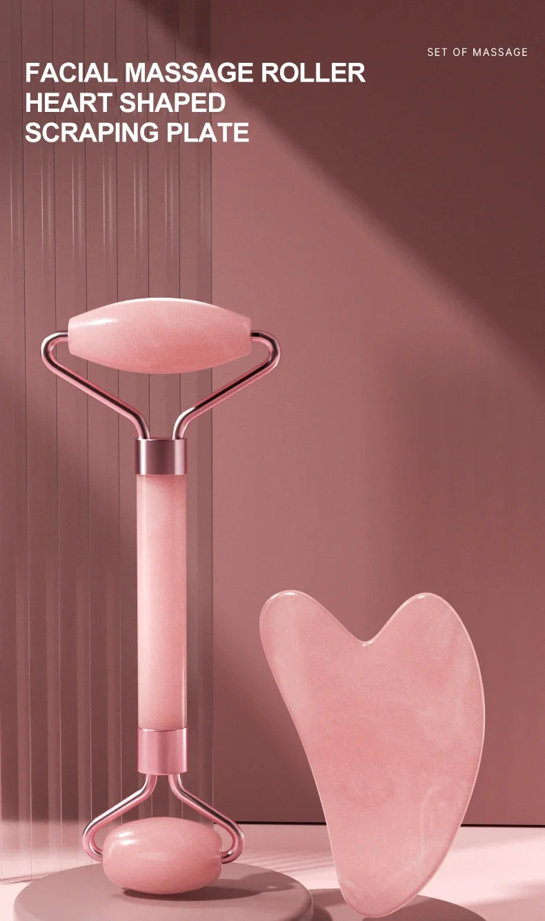 A pink heart-shaped facial massage roller with a metal handle and a separate heart-shaped scraping plate.