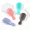 A collection of five mini travel hair brushes in various colors including pink, teal, purple, and brown.