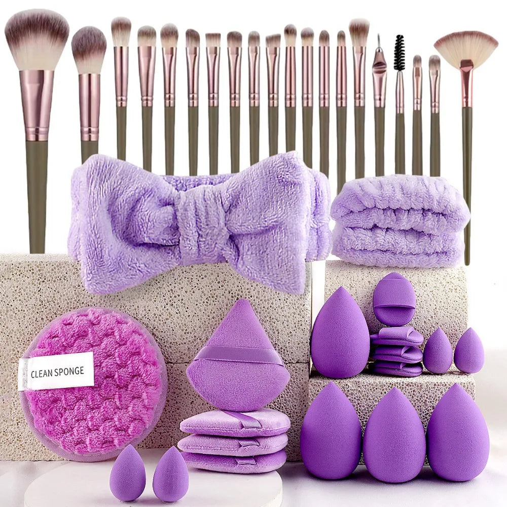 A collection of purple makeup brushes, sponges, and tools arranged on a light-colored surface.