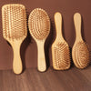 Three natural bamboo combs of varying sizes are displayed on a wooden surface.