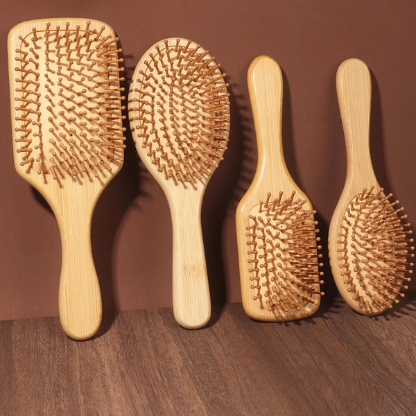 Three natural bamboo combs of varying sizes are displayed on a wooden surface.