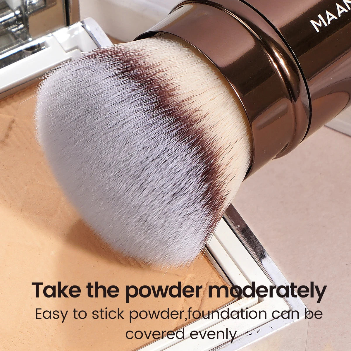 A close-up of a brown makeup brush with a fluffy, gradient pink and brown synthetic hair, shown next to a palette.