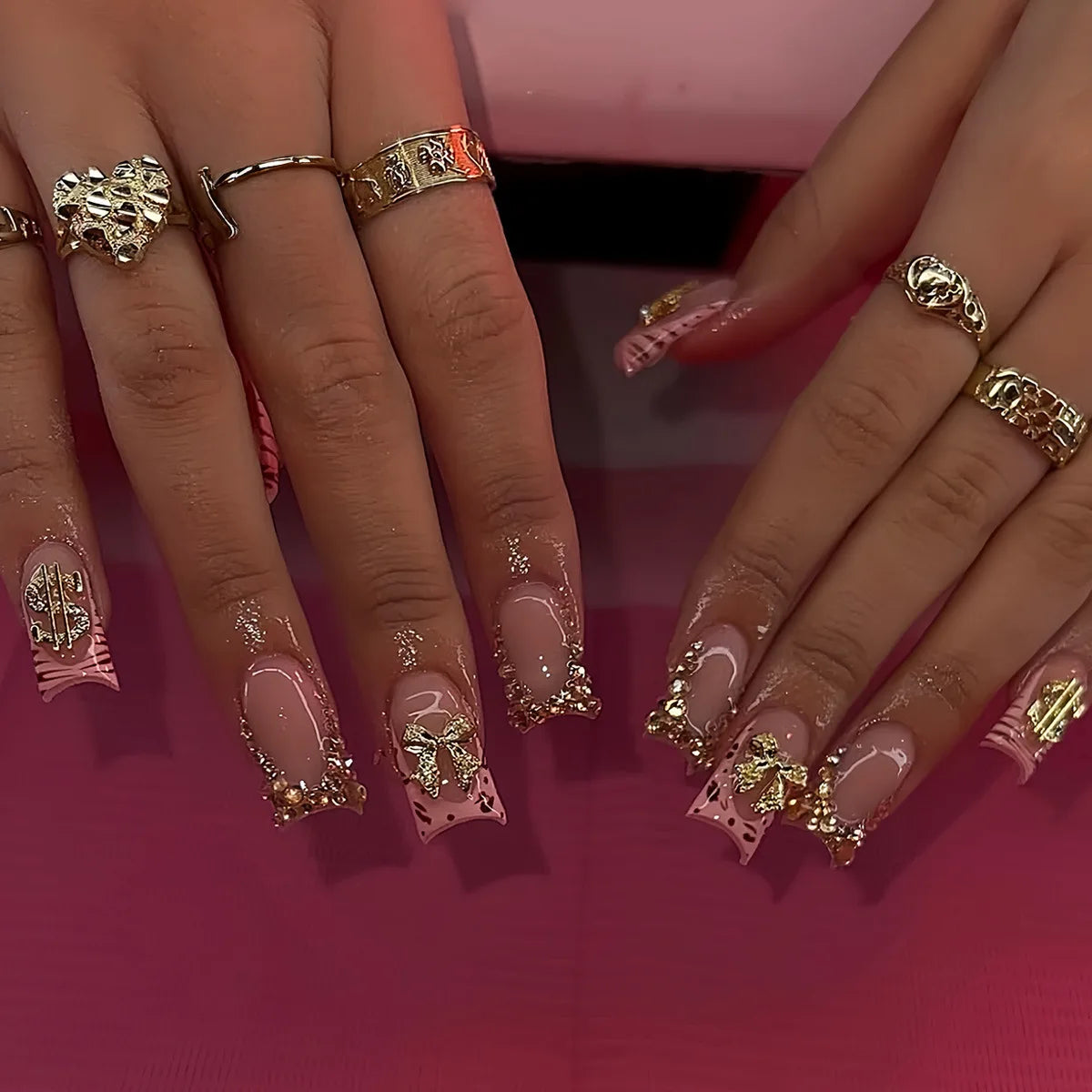 A close-up of hands displaying nude pink press-on nails with leopard print and 3D charms on a set.
