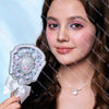 A woman holds a silver pearl hand mirror for makeup and beauty.